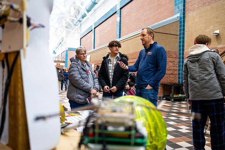 A professor speaks with a student and their parent in the atrium of the Engineering and Technology Building.