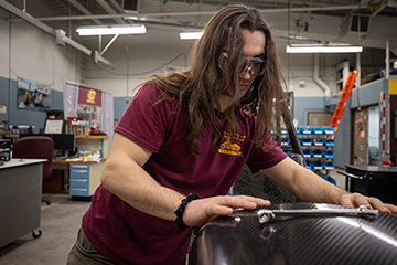 An engineering student works on a race car inside a garage.