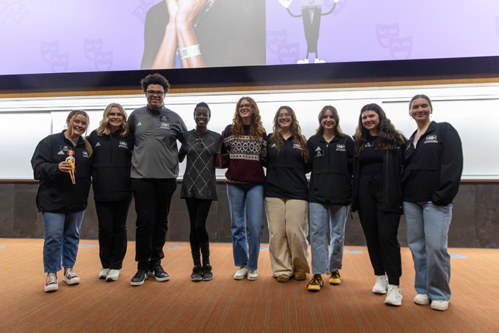 A group of students stand with comedian Maggie Maye.