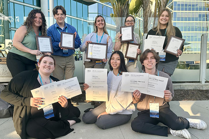 Eight young people in two rows holding up award certificates.