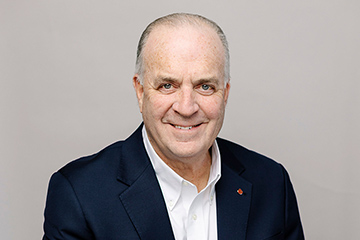 Dan Kildee wearing a dark suit coat and a white collared shirt.