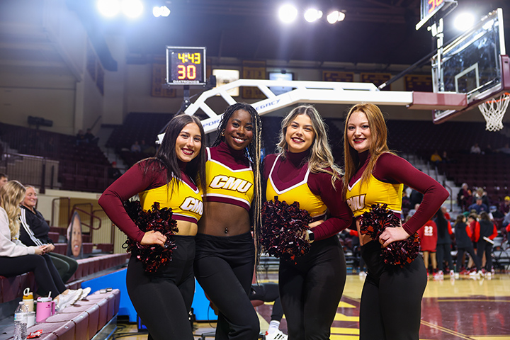 Four members of the CMU dance team pose for a photo on the basketball court.