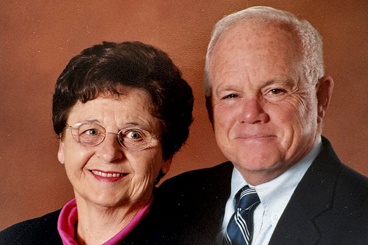 A close-up portrait of a married couple wearing business attire.