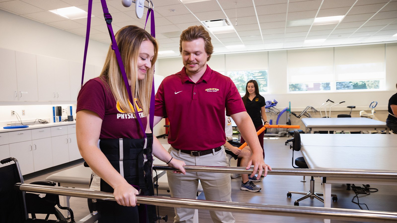 A male student working with a female student in a physical therapy lab.