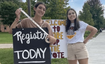 Students holding signs and stickers encouraging students to register to vote