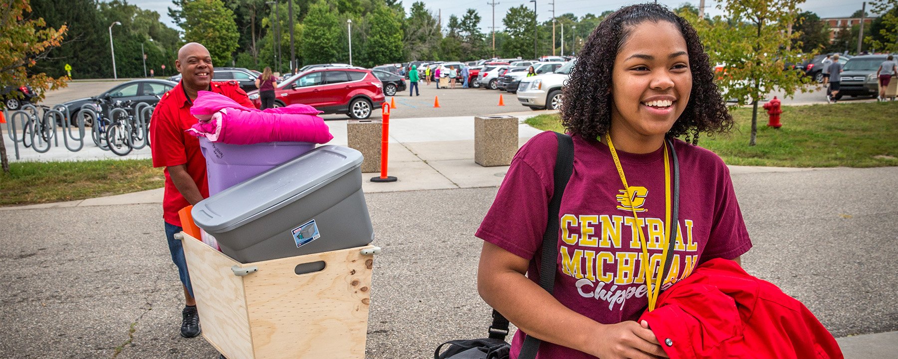 A student and their parent/supporter move items into to the residence halls using a wheeled