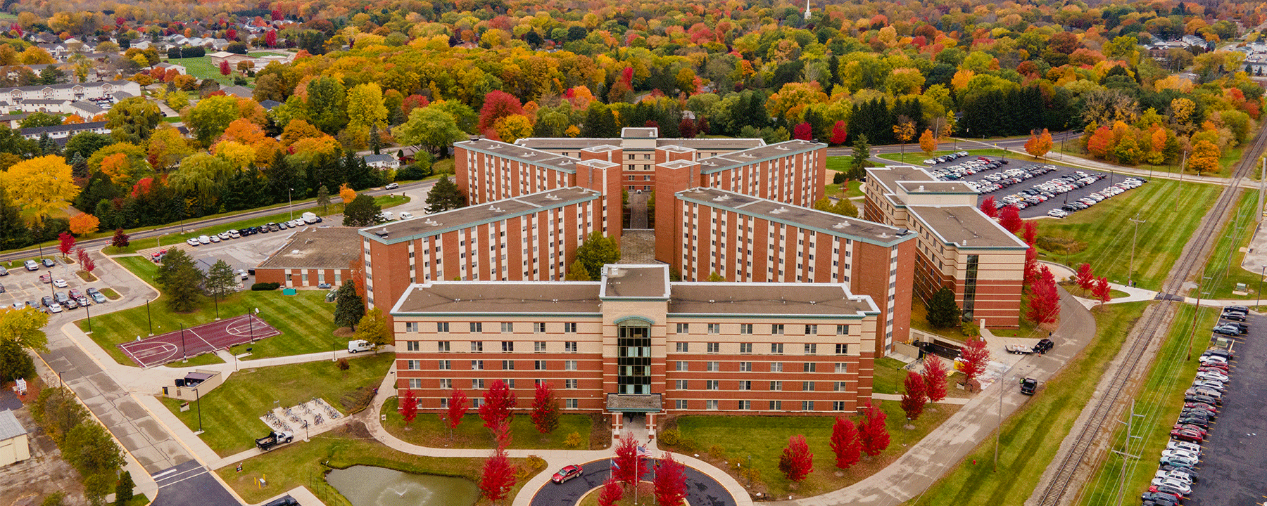 Aerial image of Towers Residence Hall on Central Michigan Universities campus, showing fall foliage of red, orange, and green trees as well as green grass.