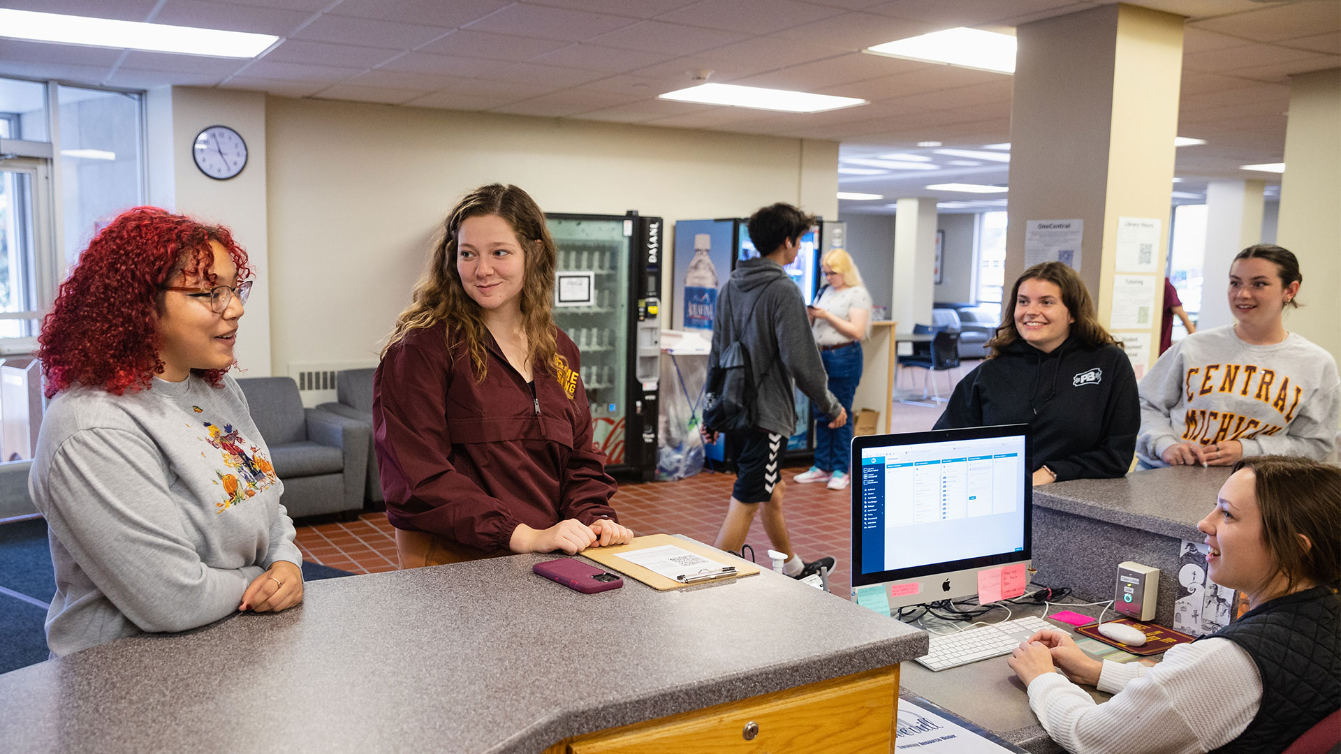 Students talking to residence life coordinator at the front desk of Sweeney Hall.