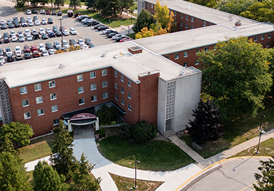 Aerial view of Thrope Hall on Central Michigan Universites campus with side walks, green grass and a parking lot filled with cars.