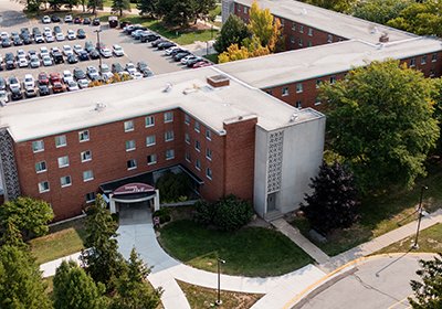 Aerial view of Thrope Hall on Central Michigan University's campus with side walks, green grass and a parking lot filled with cars.