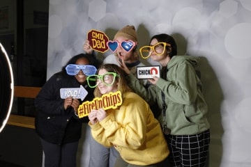 Students pose for a group shot at Fire Up All Night holding signs and wearing costume gear