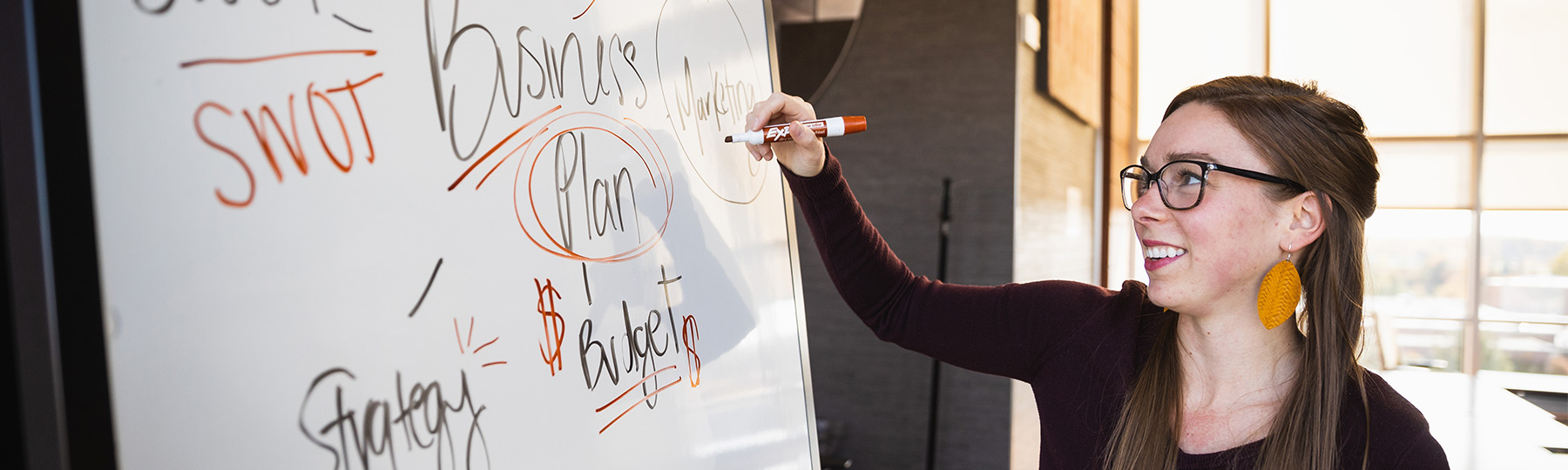 Female Master of Business Administration graduate student working on a white board.