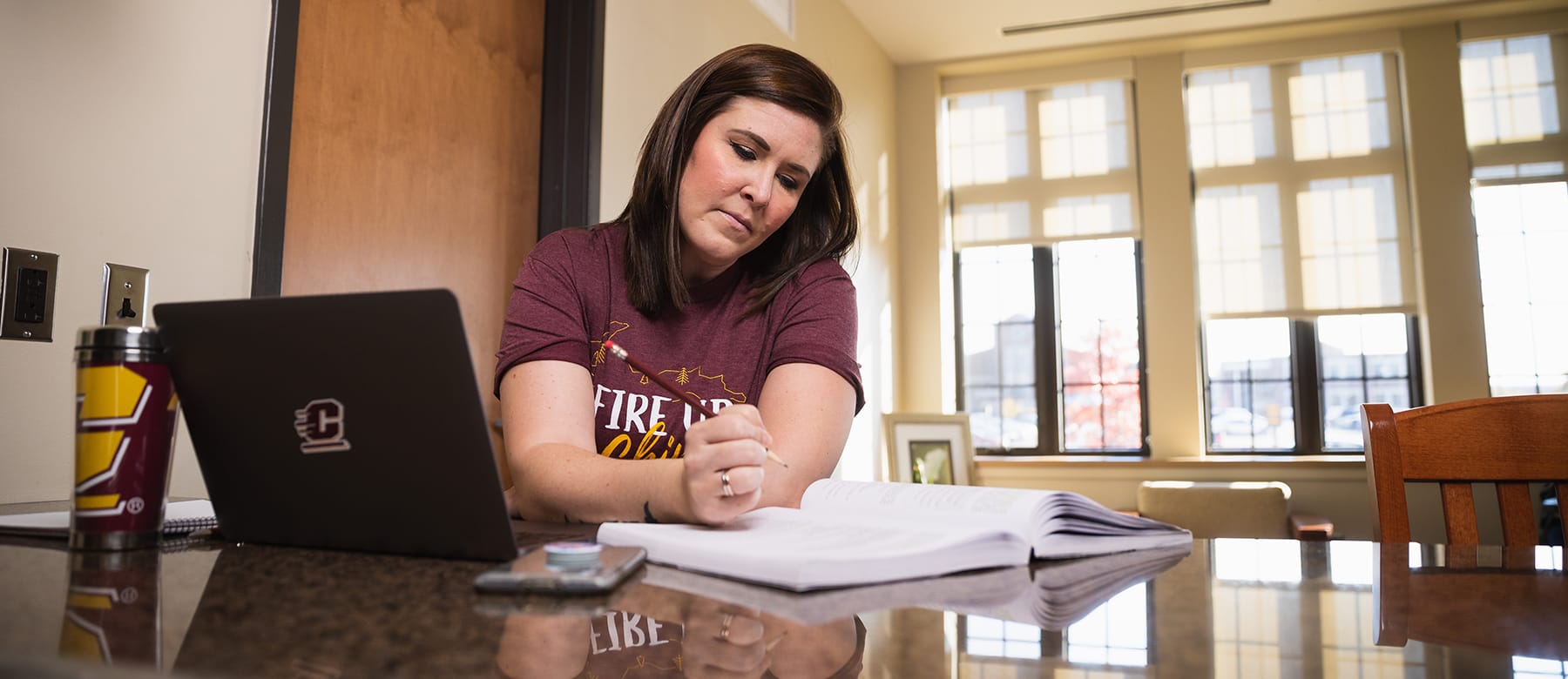 An online student wearing a maroon shirt while working at a computer completes online orientation.