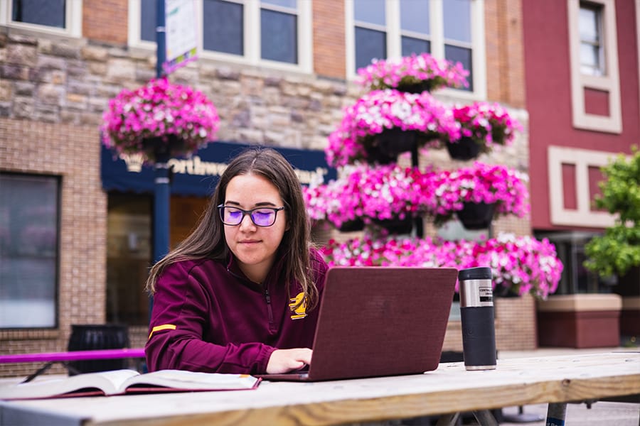 An online student wearing glasses working at a laptop completes orientation.