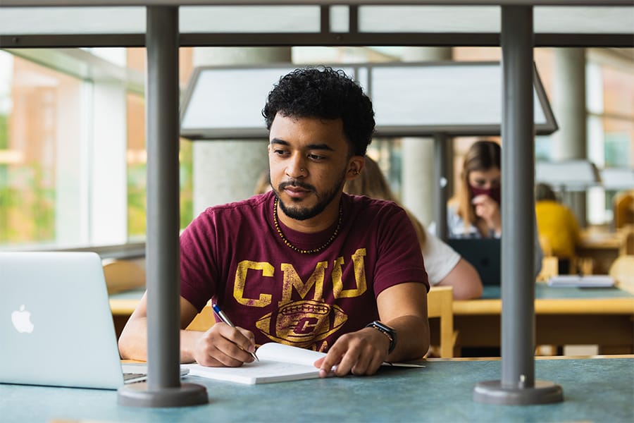 An online student in a CMU shirt completes orientation using his laptop.