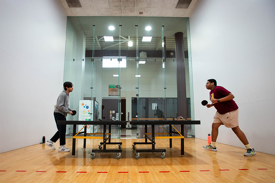 Two students are playing an intense game of table tennis (ping pong) in the Student Activity Center.