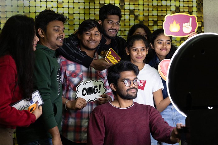 A group of students smile for a photo booth-style photo in front of a camera and ring light at the International Cultural Expo.