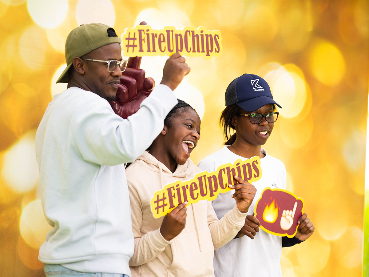 A group of three students holding Fire Up Chips signs