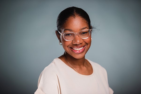 Professional headshot of a smiling Chelsea Wysinger wearing a beige shirt against a light grey background.