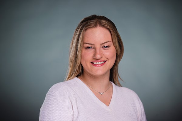 Professional headshot of a smiling Lauren Allen wearing a white shirt against a light grey background.