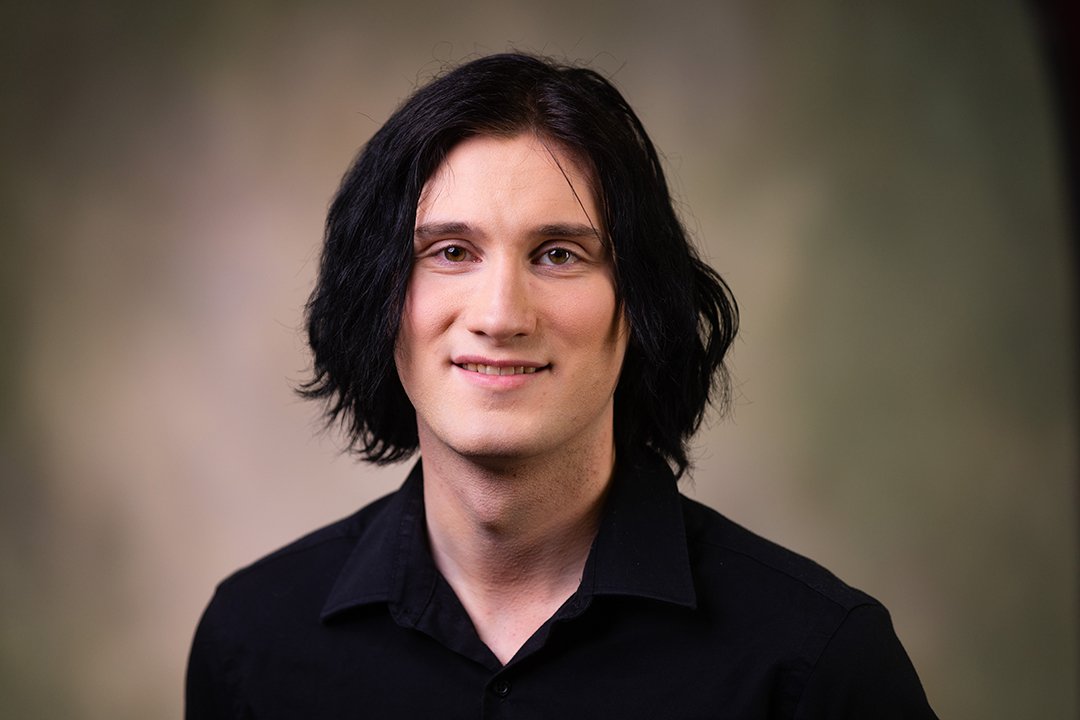 Professional headshot of Phoenix Knipe wearing a black button-up shirt while looking at the camera.