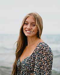 SI Leader Carly Raymo posing for a professional headshot with a body of water as the background.