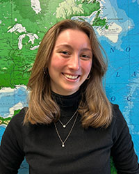 a woman smiling in front of a map.