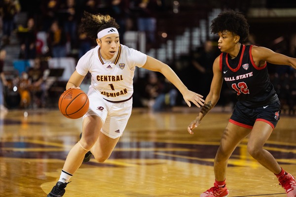 CMU women's basketball player dribbling past an opposing defender.