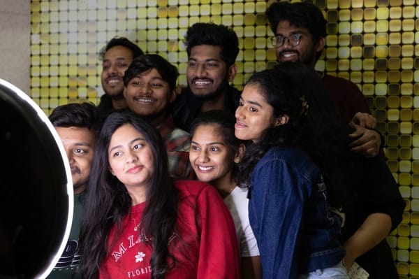 A group of diverse CMU students posing for a photo in front of gold background.