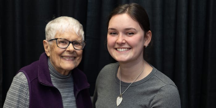 Two women smiling in front of black background.