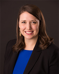 Mara D'Amico previous headshot smiling with teeth shoulder-length brown hair wearing a black blazer and blue top.