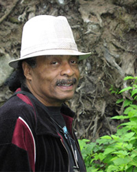 Joseph Scott is outside wearing a black shirt and white bucket hat.