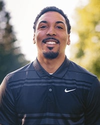 This is a headshot photo of Jamar outdoors wearing a black top.