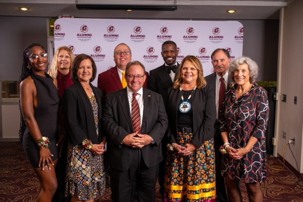 A group photo of men and women in semi formal attire for the Alumni Awards banquet.