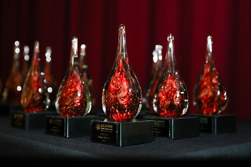 Several teardrop shaped glass trophies sit on a table.