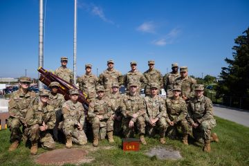 Seventeen CMU ROTC Cannon Club soldiers dressed in army fatigues pose with their Pack 75 Howitzer Cannon.